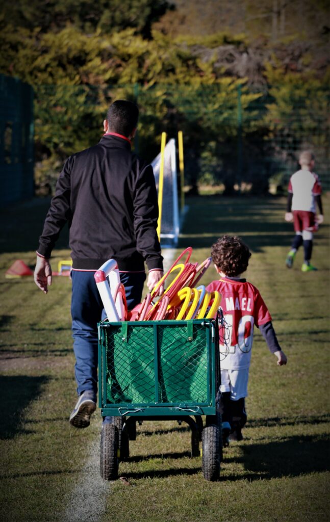 Entraineur et jeune joueur tirant le chariot du matériel d'entrainement